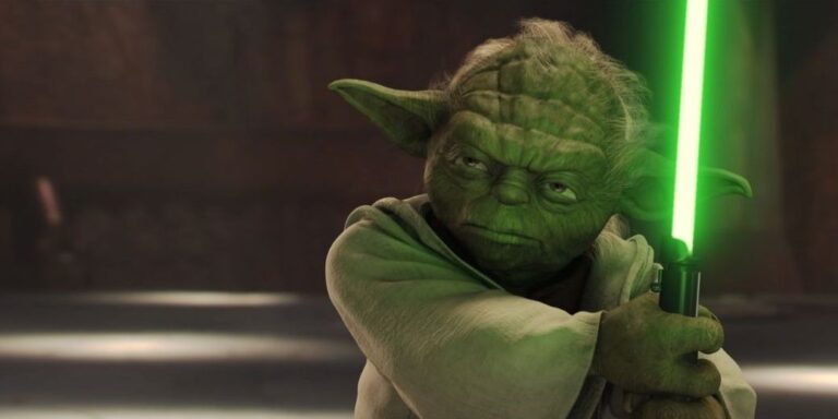 Cybersecurity Persona Quiz 2 Close‑up of the Star Wars character Yoda, a small green alien with large pointed ears and wrinkled skin, holding a glowing green lightsaber in a defensive stance against a dark, blurred background.