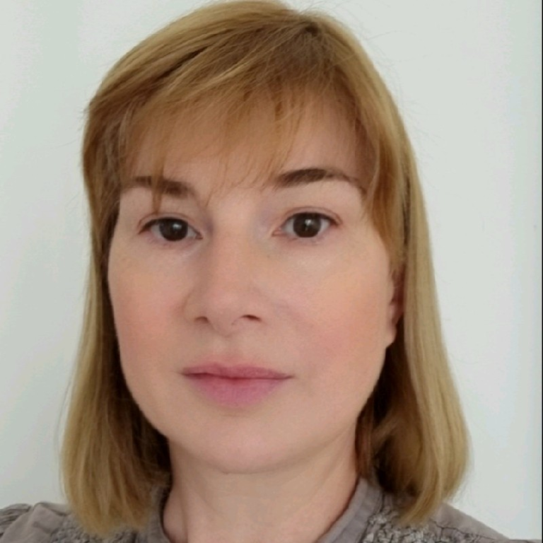 Front‑facing headshot of a person with straight, shoulder‑length light brown hair and a neutral expression, looking directly at the camera against a plain light background.